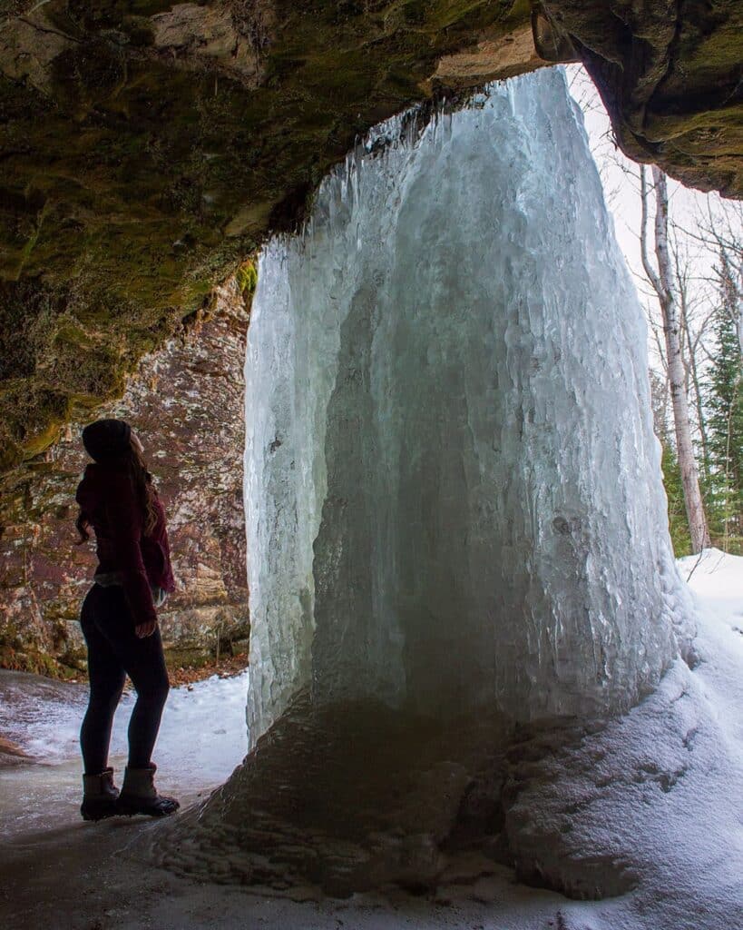Woman standing and looking at the frozen Scott Falls